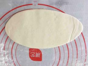 将醒发好的小面团压扁擀成长椭圆形。