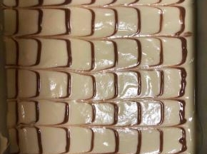 可可粉用一点点开水化开，加入一勺蛋糕糊搅拌均匀装入裱花袋，其余蛋糕糊倒入模具中，用刮刀刮平，用力震几下，然后横着挤几条可可蛋糊，再用筷子竖着划几条