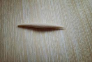 取一小块面团。用手掌心来回搓，搓成鱼鱼状，如图。