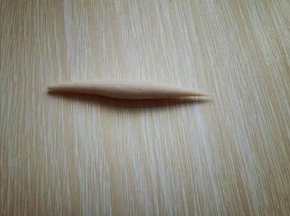 取一小块面团。用手掌心来回搓，搓成鱼鱼状，如图。