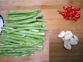小米椒切段，蒜拍碎，豆角切长条从中间对半切开。