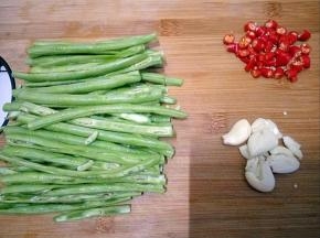 小米椒切段，蒜拍碎，豆角切长条从中间对半切开。