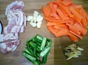 胡萝卜洗净切片，辣椒切段，蒜拍碎，姜切丝，培根切开。