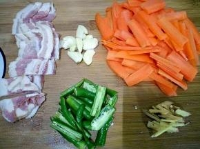 胡萝卜洗净切片，辣椒切段，蒜拍碎，姜切丝，培根切开。