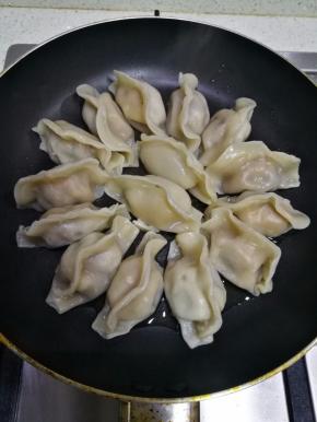 将饺子整齐摆放在平底锅内，小火把饺子底煎到微黄。
