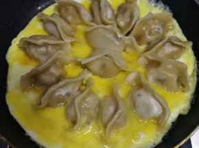 沿锅边倒入，使蛋液摊平平底锅底。