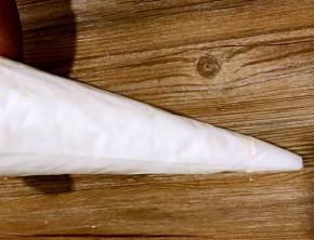 将打发好的蛋白装入裱花袋里，将裱花袋上口拧紧，用剪刀将下面尖尖剪一小口