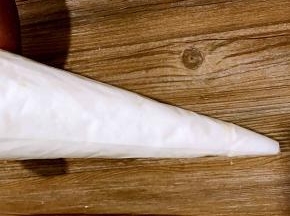 将打发好的蛋白装入裱花袋里，将裱花袋上口拧紧，用剪刀将下面尖尖剪一小口