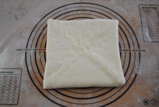 取出冰箱里的面片，擀成大约22CM大小的正方形，放入黄油，包住捏紧收口