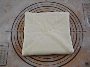 取出冰箱里的面片，擀成大约22CM大小的正方形，放入黄油，包住捏紧收口
