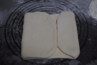 用擀面杖擀成长方形的面片，用力要均匀，把两段没有黄油的地方切除