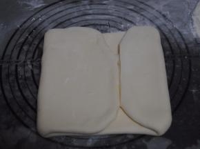 用擀面杖擀成长方形的面片，用力要均匀，把两段没有黄油的地方切除