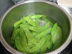 锅内加盐、几滴食用油烧开，倒入荷兰豆焯水至断生后捞出过冷水备用