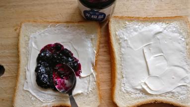 奶酪上涂抹一层蓝莓果酱，果酱涂抹在一片吐司上即可