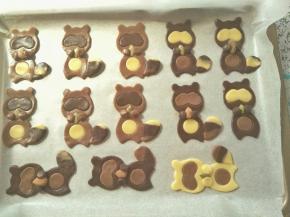 给每个小浣熊摆上一个干果仁，再把事先刻出来的小圆面团沾点蛋液组装上，尾巴亦一样沾点蛋液组装上