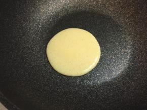 不粘锅烧热，保持小火，不放油，舀起一勺玉米面糊，从约30厘米处低落，自然形成圆形。每舀一勺的量要相同，确保每个饼的大小一致。