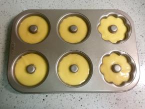 在裱花袋底部剪一个口，把面糊挤入甜甜圈模具中，我用的是学厨的不粘模具，如果是硅胶的，要先刷一层油防粘。挤到8分满即可，然后震出气泡。