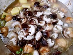 鸡翅上色均匀后放入土豆和香菇加入清水，盖上盖子中火炖。