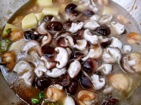 鸡翅上色均匀后放入土豆和香菇加入清水，盖上盖子中火炖。