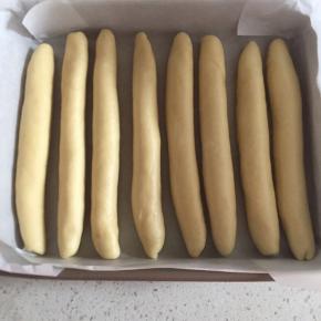 把卷好的条儿搓成长条，整齐摆放入烤盘，发酵箱发酵至两倍大。