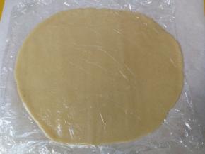 松弛后的面团取出，放在跟烤盘大小一致的油纸上，然后用擀面杖擀成厚度约0.3cm的面片（如果夏天天气热，面团回温太快，会与擀面杖粘连，可以在面团上垫一张保鲜膜再用擀面杖擀）