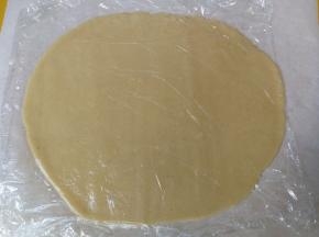 松弛后的面团取出，放在跟烤盘大小一致的油纸上，然后用擀面杖擀成厚度约0.3cm的面片（如果夏天天气热，面团回温太快，会与擀面杖粘连，可以在面团上垫一张保鲜膜再用擀面杖擀）