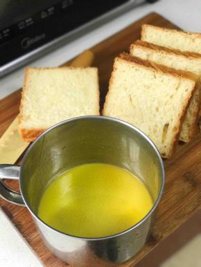 黄油隔热水融化成液体，将吐司放入黄油里面，用手按压吐司片，将黄油均匀的涂抹在吐司片上