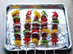 将彩椒、洋葱块和腌制好的肉块串在竹签上，基本是一块彩椒一块肉，洋葱可以少串一些，然后两面刷油，烤箱预热，200度，肉串放烤网上于烤箱中层烤制，烤盘上铺锡纸放在烤箱下层接油，烤串两面各烤制12分钟，就是先烤12分钟，再翻面烤12分钟，总共24分钟哦，具体情况看烤箱温度和肉块大小