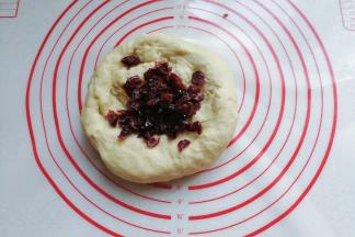 将发酵好的面团取出加入适量蔓越莓干，挤压排气揉均匀；