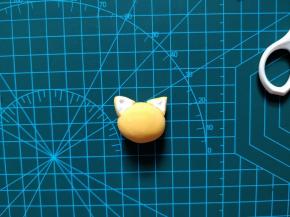 取一块橘色翻糖皮，如图捏出头部和耳朵。粘合的部分可以用少许热水蘸一下翻糖皮，或者用翻糖皮粘合剂。