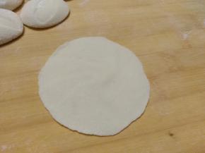 从外边向内擀圆饺子皮，中间厚一点边上薄一点