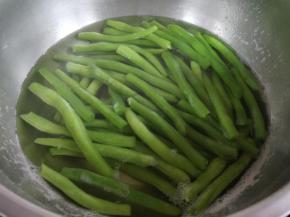 沸水中加盐，将豆角放入稍煮到半熟（颜色变成深绿色）。这样豆角更容易入味，且节省干煸的时间，因为没有熟透的豆角有毒性，千万不能食用。要沥净水份，不然后来煸炒的时候很容易喷溅烫着哦。