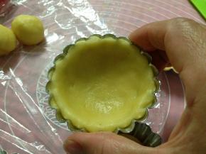 取一小块挞皮面团，用两手的拇指将它捏成塔模的形状