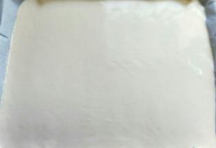 用刮板将蛋糕糊刮平，烤盘垂直震几下，震出气泡。