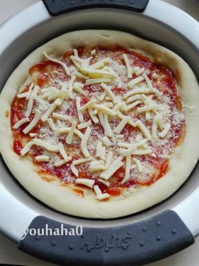 披萨饼抹上少许的番茄沙司，撒上适量的芝士粉，撒一层奶酪丝