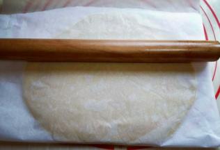 静止后的面团放在案板上，上下各垫上一张油纸，用擀面杖将其擀薄，约2mm样子。