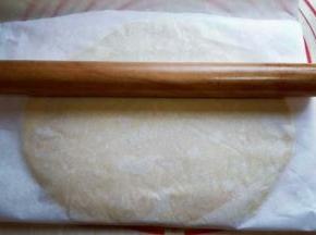 静止后的面团放在案板上，上下各垫上一张油纸，用擀面杖将其擀薄，约2mm样子。