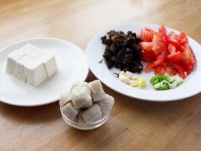 2．豆腐切方块，木耳随意切几刀，番茄切小块，葱蒜切碎，鱼丸切成小块。