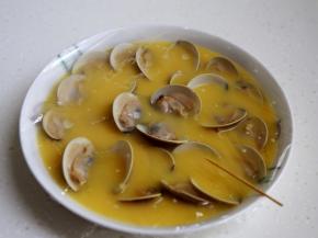 9.将煮开口的蛤蜊一个个地摆在盘中，蒙上微波炉专用保鲜膜，用牙签扎些小洞。注这样做蒸出的蛋就不会有小孔。
