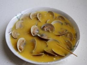 9.将煮开口的蛤蜊一个个地摆在盘中，蒙上微波炉专用保鲜膜，用牙签扎些小洞。注这样做蒸出的蛋就不会有小孔。
