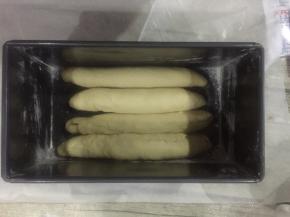 吐司盒子里拍上面粉，虽然这个盒子是不粘模具，但我试下来还是磕了面粉比较好脱模。

包好的面团这样子排放。