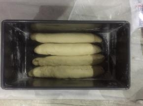 吐司盒子里拍上面粉，虽然这个盒子是不粘模具，但我试下来还是磕了面粉比较好脱模。

包好的面团这样子排放。