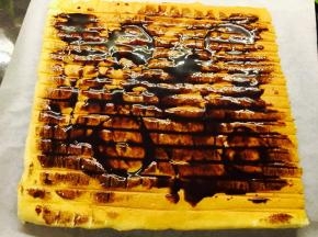 出炉后，倒扣于烤网上。撕去油纸。涂上巧克力酱。