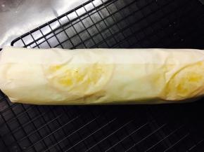 用油纸卷起来。卷好后，不要拿掉油纸，包裹着油纸，放入冰箱冷藏定型后，再拿出来切。