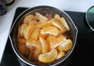 把桔子倒入锅中；