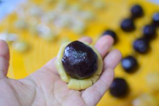 再把面团按扁，把刚才包好的豆沙蛋黄放在面上