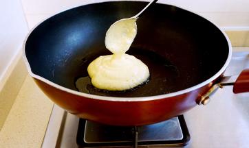 小火，将舒芙蕾糊均匀的滴落进平底锅中，然后再加一勺，这样可以增加松饼的厚度