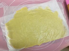 然后将酥皮放入大张的油纸或保鲜膜里用擀面杖擀成均匀的薄片
