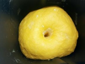 面粉的吸水性不同，请根据实际情况调整南瓜泥的用量，揉成一个柔软的面团。面团揉好以后，放在面包机里，盖上湿布，室温下发酵至2倍大，手指沾面粉轻轻插入面团里，拔出手之后孔洞不会塌陷也不会回缩，就表示发酵好了。