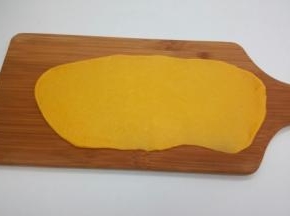 将发酵好的面团放在案板上，排出面团内部的气体，分成10小份，盖上保鲜膜醒发15分钟案板上撒一些面粉防粘，将一个醒发好的小面团压扁，并用擀面杖擀成长条形